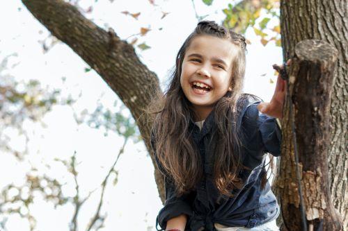 kid smiling in tree | tooth extraction Dubuque, IA